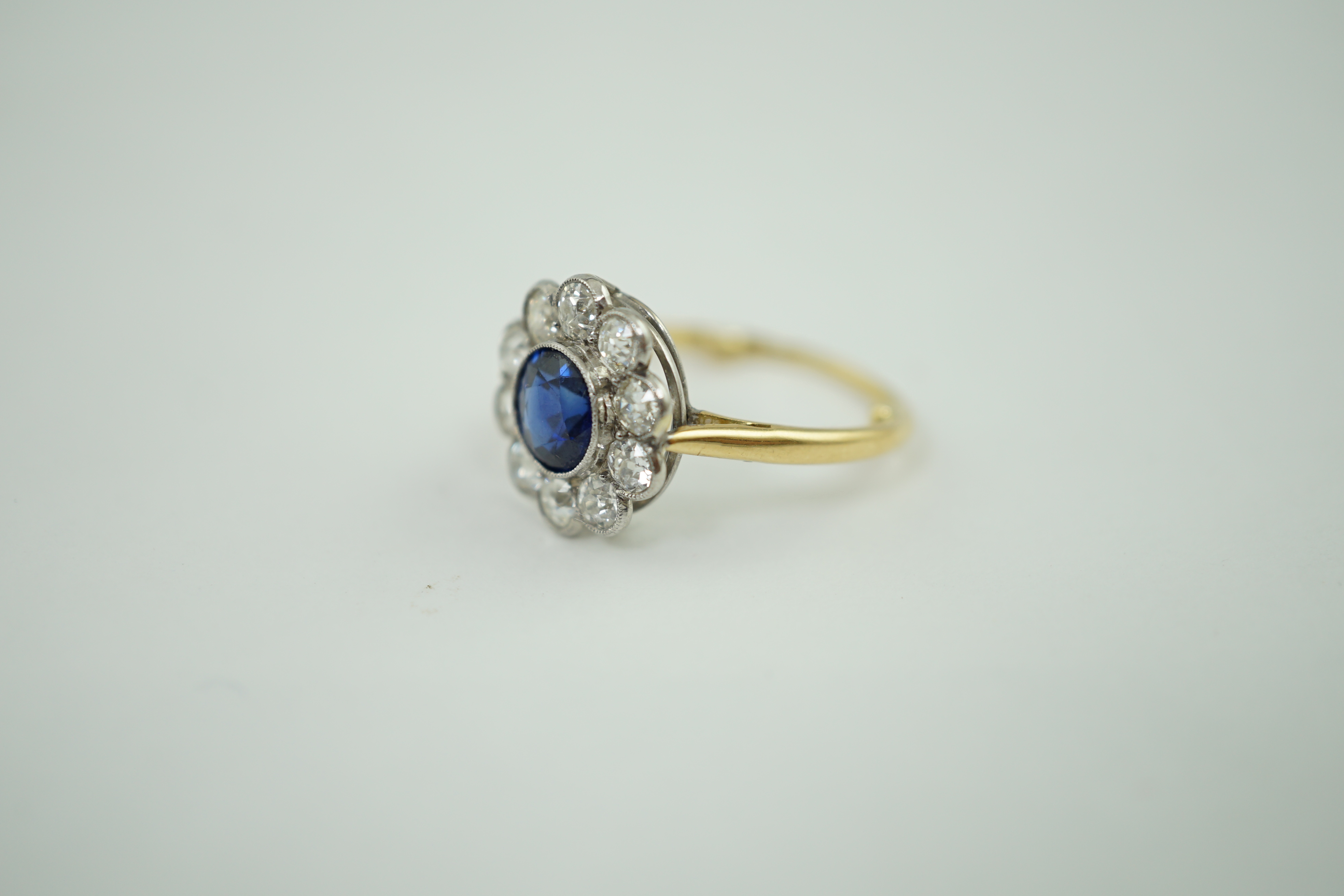 A mid 20th century gold, sapphire and millegrain set diamond flower head cluster ring